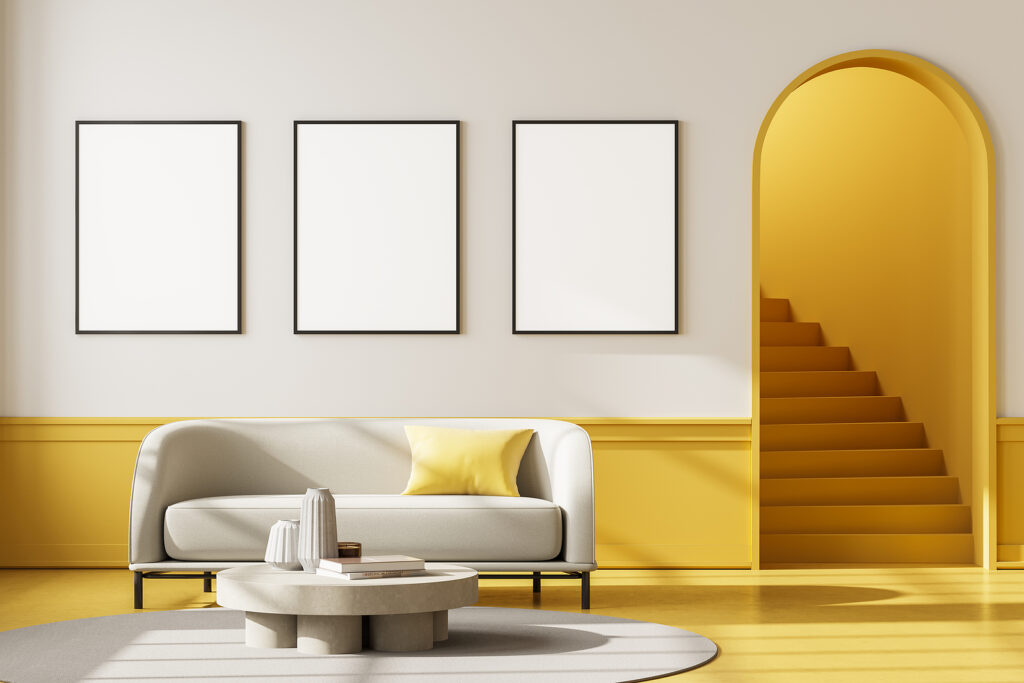 Apartment interior with white couch and coffee table on carpet with yellow floor. Mockup blank wall copy space with three posters, staircase with arch door, 3D rendering